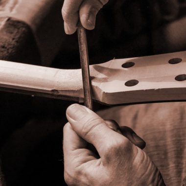 hands using tool to cut wood into headstock