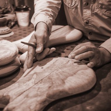 hands measuring piece of wood to make electric bass