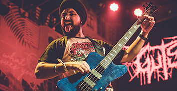 Gurdip Singh Narang playing blue electric bass in concert