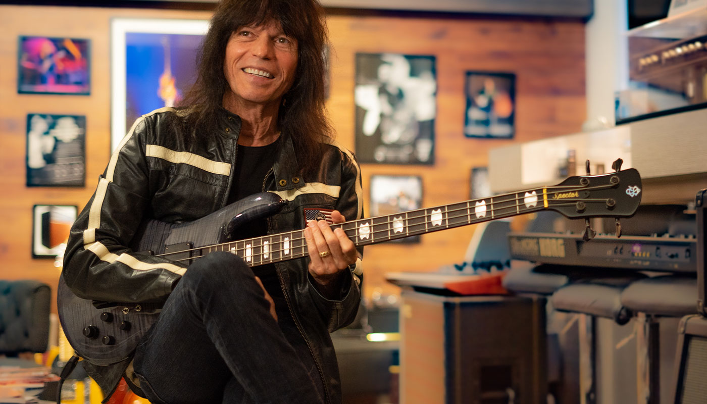 Guy smiling and holding a Spector bass in a studio room