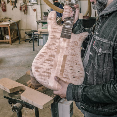man holding unfinished Spector bass in workshop