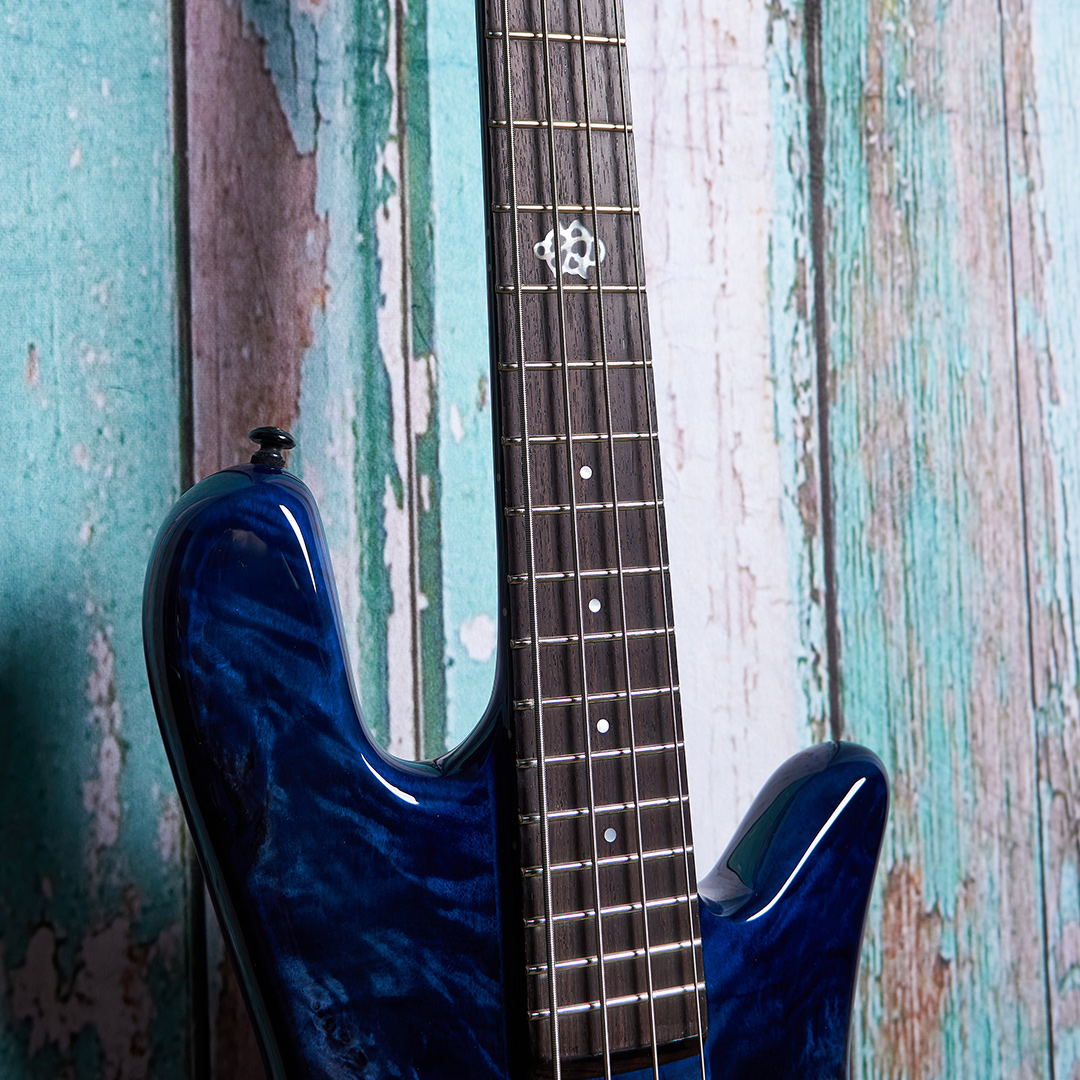 top of blue Spector bass body in front of blue wood panels