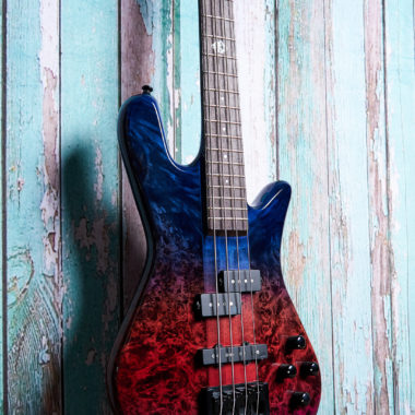 body of blue and purple Spector bass in front of blue wood panels