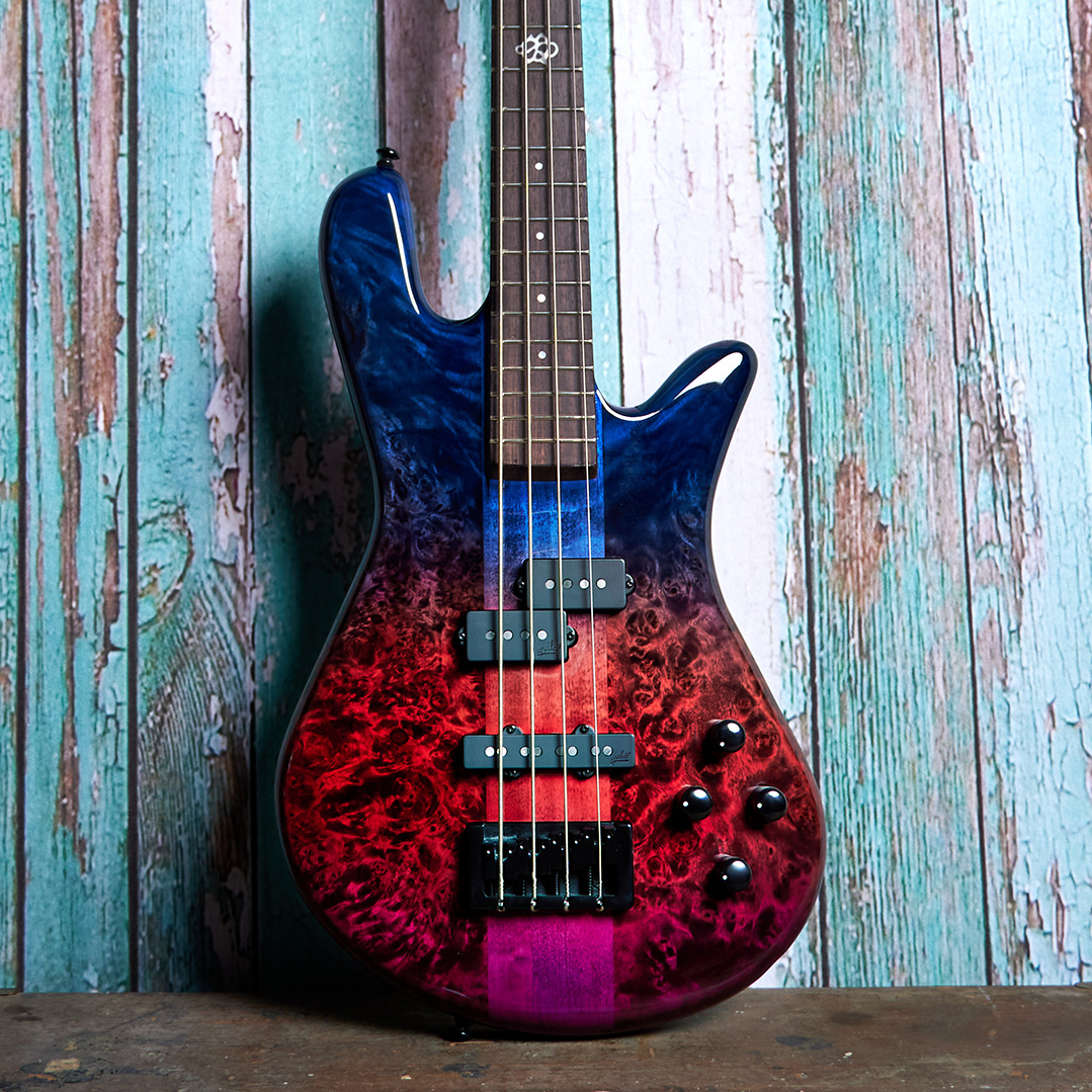 body of blue and purple Spector bass in front of blue wood panels