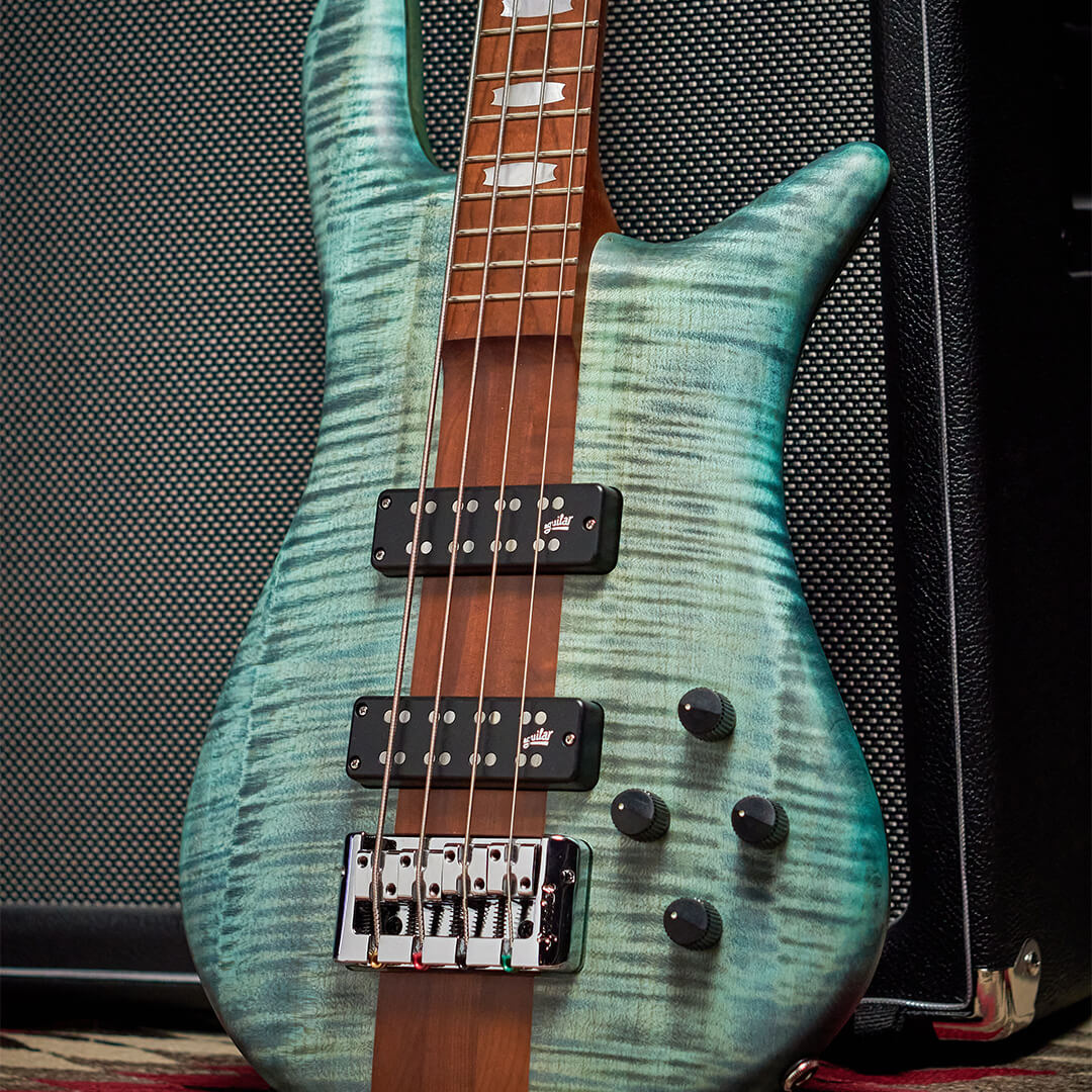 close up of Euro RST bass guitar body in Turquoise Tide matte finish leaned against a black amp
